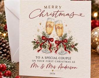 May include: A square greeting card with a cream background featuring two champagne flutes tied with red ribbons, holly, and berries. Text reads: MERRY Christmas TO A SPECIAL COUPLE ON YOUR FIRST CHRISTMAS AS Mr & Mrs Anderson 2026.