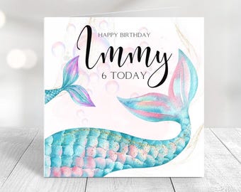 May include: A birthday card featuring a mermaid tail with blue and pink scales and the text "Happy Birthday Immy 6 Today".