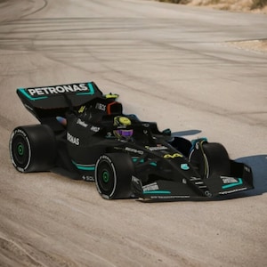 May include: A black Formula 1 race car with the word "PETRONAS" on the rear wing. The car is on a race track with a sandy surface.