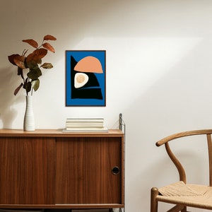 A simple yet minimalist art poster hung on a wall, surrounded by a beautiful Scandinavian house with wooden table and minimalist wooden chair. The art piece made by an Artist named Kalamasa Art Gallery and can be downloadable through Etsy.