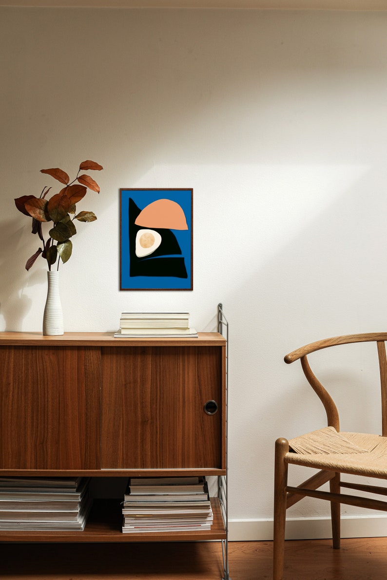 A simple yet minimalist art poster hung on a wall, surrounded by a beautiful Scandinavian house with wooden table and minimalist wooden chair. The art piece made by an Artist named Kalamasa Art Gallery and can be downloadable through Etsy.