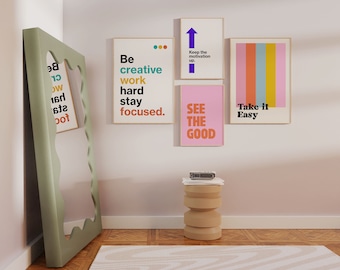 May include: A collection of framed art prints with motivational quotes and colorful abstract designs. The prints include phrases like "Be creative, work hard, stay focused" and "See the good." A large, sage green mirror leans against the wall.