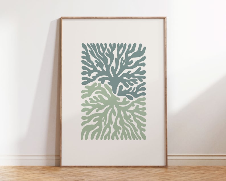 K&ouml;nnte beinhalten: Ein gerahmter Kunstdruck mit einem stilisierten botanischen Design. Das Kunstwerk zeigt zwei sich &uuml;berlappende korallenartige Formen in Gr&uuml;n- und Blaugr&uuml;nt&ouml;nen vor einem cremefarbenen Hintergrund. Der Rahmen hat einen warmen, nat&uuml;rlichen Holzton.