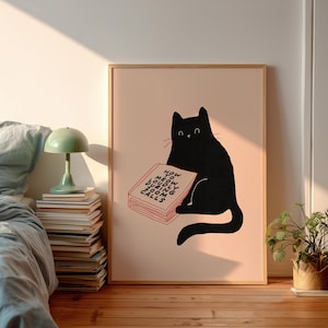 Può includere: Una stampa artistica incorniciata presenta un gatto nero che legge un libro con il testo "How to Meow Loudly During Zoom Calls" in rosso. Il gatto è sagomato su uno sfondo rosa chiaro. La stampa è in una cornice di legno.