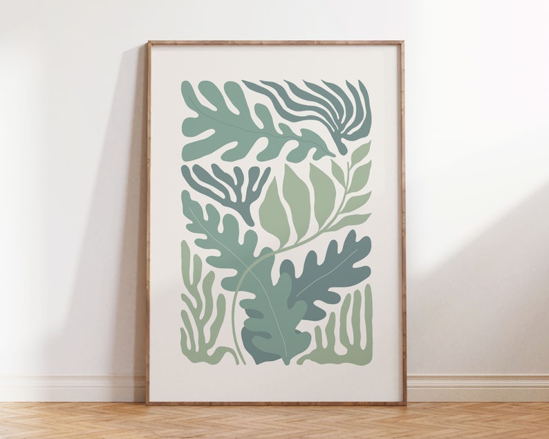 K&ouml;nnte beinhalten: Ein gerahmter botanischer Druck mit stilisierten gr&uuml;nen Bl&auml;ttern in verschiedenen Formen und Schattierungen auf cremefarbenem Hintergrund. Das Kunstwerk ist in einem hellbraunen Holzrahmen eingefasst, ideal f&uuml;r die Wanddekoration. Der Druck hat eine moderne, minimalistische &Auml;sthetik.