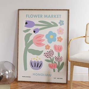 May include: A framed poster with a colorful illustration of flowers. The poster is titled "Flower Market" and has the text "Honolulu" and "Pastel Edition" at the bottom. The poster is framed in a light brown wood frame.