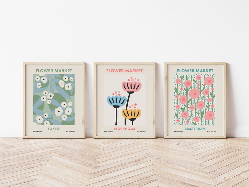 May include: Three framed prints with a floral theme. Each print features a different floral design and the city name: Tokyo, Stockholm, and Amsterdam. The prints have a light beige background and the text "Flower Market" is at the top of each print.