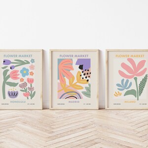 May include: Three framed prints with the title "Flower Market" and the city names Honolulu, Madrid, and Milano. Each print features a colorful abstract floral design.