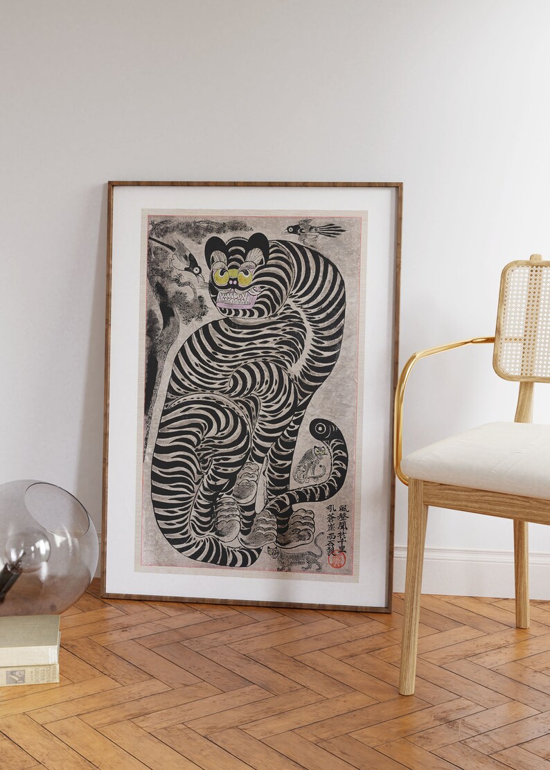 Peut inclure: Une illustration en noir et blanc d'un tigre aux yeux jaunes. Le tigre est assis sur ses haunches, la queue enroul&eacute;e autour de son corps. L'illustration est encadr&eacute;e dans un cadre en bois brun.