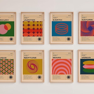 May include: Eight framed art prints featuring retro-style illustrations of the planets in our solar system. Each print has a unique color scheme and geometric design, with the planet's name at the top. The prints are in wooden frames.