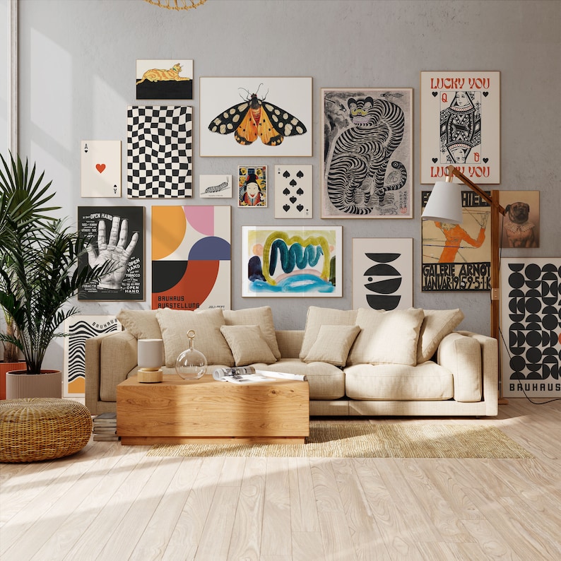 Op de afbeelding: Een woonkamer interieur met een beige bank, een houten salontafel en een verscheidenheid aan kleurrijke wandkunst, waaronder een vlinder, een geometrisch ontwerp en een handafdruk. De wandkunst hangt aan een grijze muur.