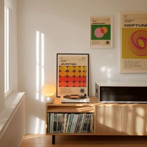 May include: A mid-century modern living room scene featuring framed posters of planets, a record player, and a wooden cabinet filled with vinyl records. The posters have colorful geometric designs. A spherical lamp sits on the cabinet.