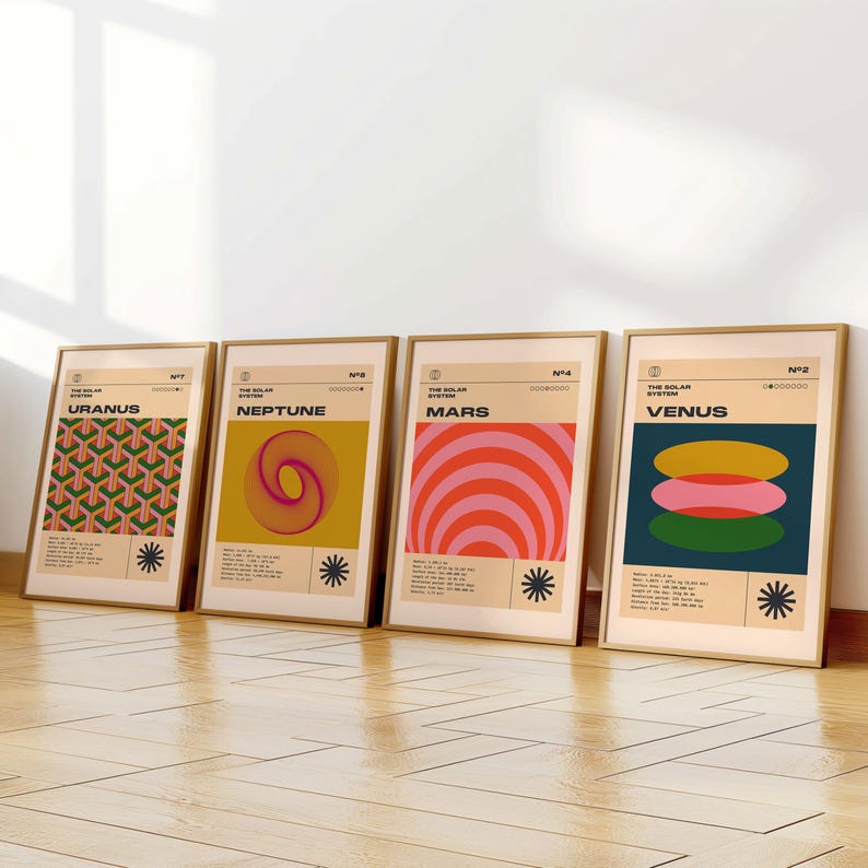 May include: Four framed art prints featuring planets from the solar system. Each print has a different design and color scheme, including geometric patterns and abstract shapes. The prints are in gold frames and are leaning against a white wall.