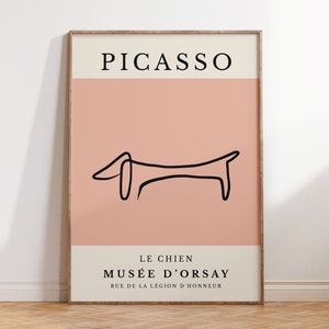 Puede incluir: Un póster minimalista con fondo rosa y un dibujo de línea negra de un dachshund. El póster tiene el texto "PICASSO" en la parte superior y "LE CHIEN MUSÉE D'ORSAY RUE DE LA LÉGION D'HONNEUR" en la parte inferior.