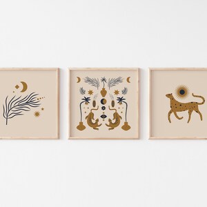 Op de afbeelding: Drie ingelijste prints met een minimalistische esthetiek. De linker print toont een gestileerde tak met een halve maan en sterren. De middelste print toont een symmetrisch ontwerp met twee gestileerde hagedissen, een halve maan, een zon en een palmboom. De rechter print toont een gestileerde cheetah met een zon erachter.