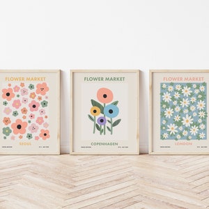 May include: Three framed prints with the title "Flower Market" and the city names "Seoul", "Copenhagen", and "London". Each print features a different floral design in a colorful, abstract style.