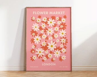 May include: A framed pink poster with the words "FLOWER MARKET LONDON" in white. The poster features a pattern of white, orange, and yellow daisy-like flowers. The words "PASTEL EDITION" and "N°4 JULY 2021" are also printed on the poster.