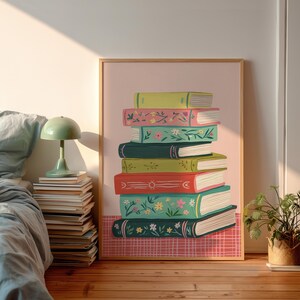 Può includere: Una stampa artistica incorniciata con una pila di libri colorati. I libri hanno copertine di vari colori, tra cui verde, rosa e rosso, con disegni floreali e solari. Lo sfondo è rosa chiaro con un motivo a scacchi rossi e bianchi nella parte inferiore.