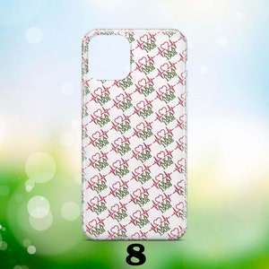 May include: A clear phone case with a white background and a repeating pattern of pink hearts with green and pink "AKA 1908" text.