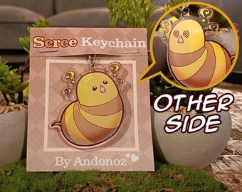 May include: A yellow and brown cartoon bee keychain with question marks above its head. The keychain is on a pink card with the text "Scree Keychain" and "By Andonoz". The other side of the keychain shows a close-up of the bee's face.