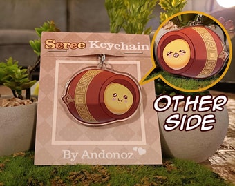 May include: A red and gold keychain with a cartoon character inside. The keychain is shaped like a barrel with a cute face and is labeled "Scree Keychain" and "By Andonoz".