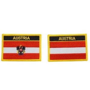 May include: Two rectangular patches displaying the Austrian flag. Each patch has a red and white striped design with a black border at the top, with the word "AUSTRIA" in white. One patch includes the Austrian coat of arms.