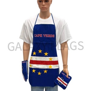Puede incluir: Un delantal de cocina azul con la bandera de Cabo Verde y las palabras "Cabo Verde" bordadas en él. El delantal lo lleva puesto un maniquí. También hay guantes para horno y un posavasos a juego.