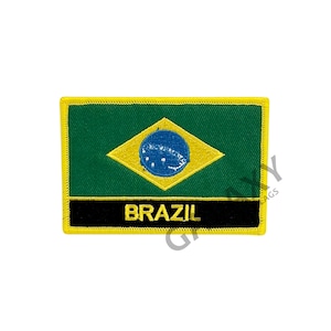 Puede incluir: Un parche bordado con la bandera de Brasil. La bandera es verde con un diamante amarillo en el centro. El diamante contiene un círculo azul con estrellas blancas. El parche tiene un borde negro con la palabra "BRASIL" en letras amarillas.