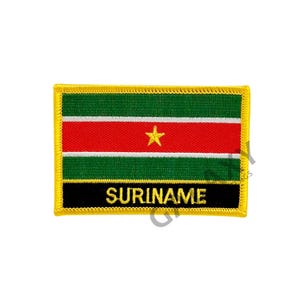 May include: A yellow embroidered patch with the flag of Suriname. The flag has green, white, red stripes with a yellow star in the center. The text "SURINAME" is written in black below the flag.