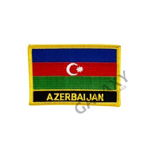May include: A yellow embroidered patch with the flag of Azerbaijan. The flag is blue, red, and green with a white star and crescent moon in the center. The words "AZERBAIJAN" are embroidered in yellow on a black background.