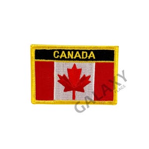 Może przedstawiać: Naszywka z kanadyjską flagą w kolorze czerwonym i białym z liściem klonu w środku. Naszywka jest otoczona czarną ramką i złotą obwódką. Słowo "CANADA" jest napisane na czarnym tle żółtym kolorem nad flagą.