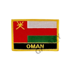 Pode incluir: Um remendo bordado com a bandeira de Omã. A bandeira é vermelha, branca e verde com um símbolo dourado no canto superior esquerdo. O remendo tem uma borda preta com a palavra "OMÃ" em letras douradas.