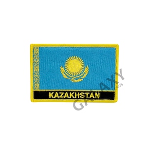 May include: Embroidered patch of the Kazakhstan flag. The patch has a light blue background with a gold sun and eagle emblem. The word "KAZAKHSTAN" is displayed in gold text on a black bar.