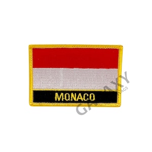 Op de afbeelding: Een geborduurde patch in rood, wit en zwart met een gouden rand. De patch toont de vlag van Monaco en het woord "MONACO" in gouden letters.