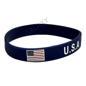 May include: A blue silicone bracelet with a small American flag and the text "U.S.A." in white.
