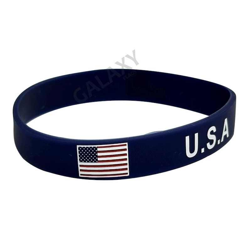 May include: A blue silicone bracelet with a small American flag and the text "U.S.A." in white.