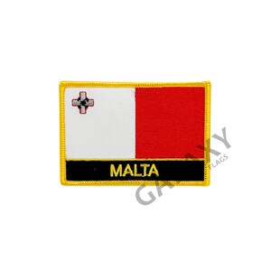 Może przedstawiać: Naszywka haftowana w kolorze czerwonym i białym z maltańskim krzyżem i napisem "MALTA" złotymi literami. Naszywka ma czarną ramkę i złoty obrys.