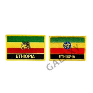 May include: Two embroidered patches featuring the Ethiopian flag. The first patch has a yellow background with a green top and red bottom stripe. It features a gold lion with a red crown and a black mane. The second patch has a yellow background with a green top and red bottom stripe. It features a blue star with a yellow outline and seven points. Both patches have a black border and a yellow outline. The text "ETHIOPIA" is written in gold on both patches.