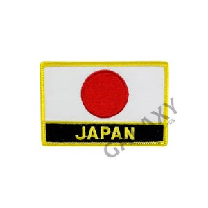 May include: A white and red embroidered patch with a yellow border. The patch features the Japanese flag with the red circle in the center and the word "JAPAN" in black letters below the flag.