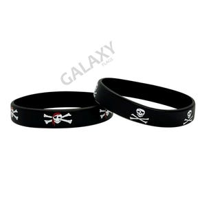 May include: Two black rubber bracelets featuring a pirate skull and crossbones design. The white skull has a red bandana. These bracelets are a fun accessory for a pirate-themed event or costume.