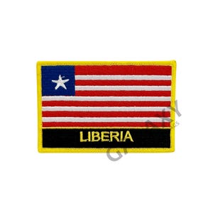 Può includere: Una toppa con bordo giallo con la bandiera liberiana, che presenta strisce rosse e bianche e un cantone blu con una stella bianca. Il testo "LIBERIA" è ricamato in oro su sfondo nero.