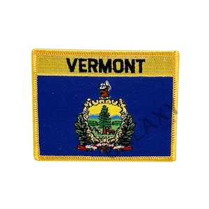 May include: A rectangular patch displaying the Vermont state flag. The top section is gold, with the word "VERMONT" in black. The lower section is blue, with the state seal in the centre, depicting a landscape with trees and a cow.