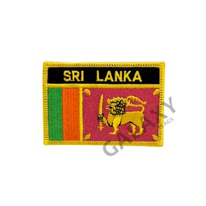 Może przedstawiać: Naszywka haftowana z flagą Sri Lanki. Naszywka jest prostokątna i ma złotą obwódkę. Flaga jest czerwona, zielona, pomarańczowa i żółta z lwem w środku. Słowa "SRI LANKA" są napisane czarnym kolorem na czarnym tle u góry naszywki.