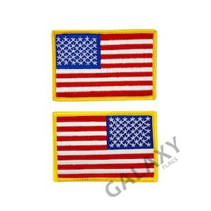 May include: Two embroidered American flag patches with yellow stitching around the edges. The flags are in opposite orientations, with the stars on the left side of one flag and the right side of the other.