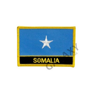 Könnte beinhalten: Ein blauer und weißer gestickter Aufnäher mit einem weißen Stern und dem Wort "SOMALIA" in schwarzem Text. Der Aufnäher hat einen gelben Rand.