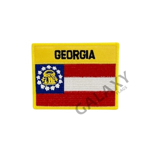 May include: A yellow embroidered patch with the state flag of Georgia. The flag features a red and white striped background with a blue canton containing a gold state seal. The text "GEORGIA" is embroidered in black on a yellow banner above the flag.