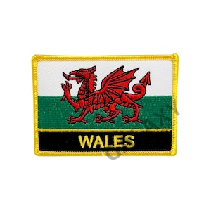 Può includere: Toppa ricamata con la bandiera gallese. Il design presenta un drago rosso su sfondo bianco e verde, con la scritta "WALES" in oro su uno stendardo nero. La toppa ha un bordo giallo.