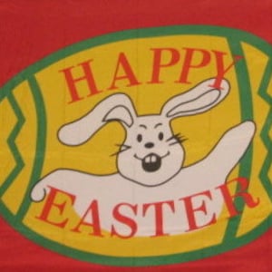 May include: A red fabric banner with a yellow and green oval design. The oval features a white bunny with a happy expression and the text "HAPPY EASTER".