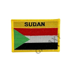 May include: A yellow embroidered patch featuring the flag of Sudan. The flag has a green triangle, a black stripe, a white stripe, and a red stripe. The word "SUDAN" is embroidered in black letters above the flag.
