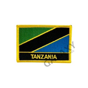 May include: A yellow-bordered patch with the Tanzanian flag. The flag features a green, black, and blue design with the word "TANZANIA" in yellow lettering.
